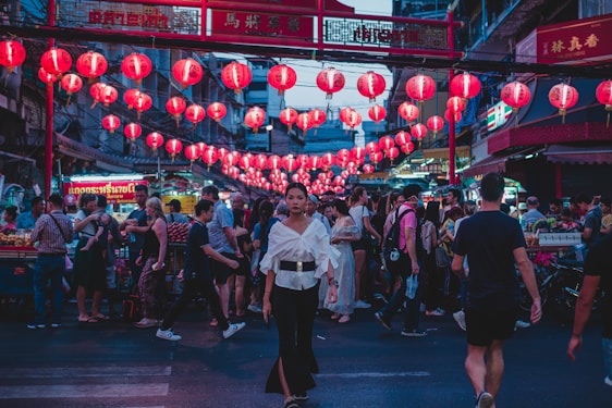 A vibrant street scene in Guangzhou at dusk, with glowing red lanterns and bustling market stalls.