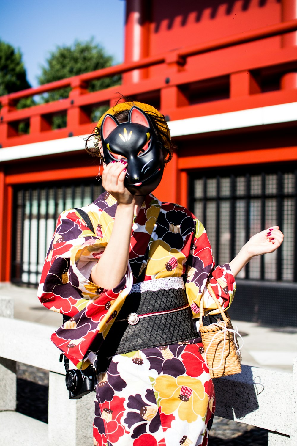 red, yellow, black, and white kimono and holding black mask