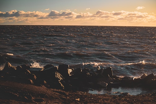 Ocean waves gently crashing on a rocky shore at sunset.