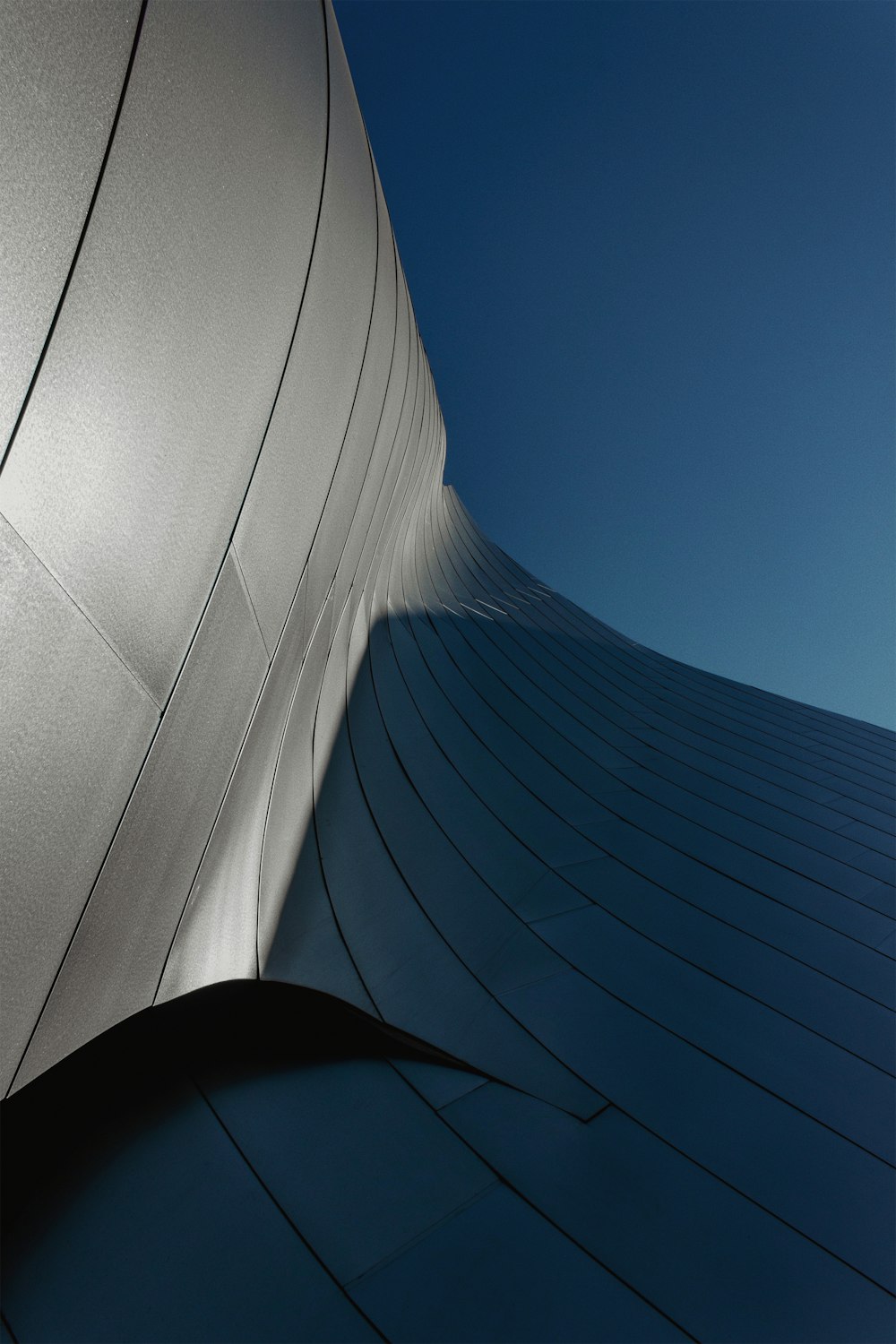 a curved building with a blue sky in the background