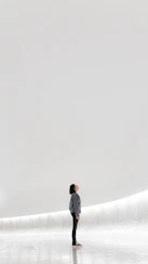 A person in a denim jacket looking up in a minimalist white space