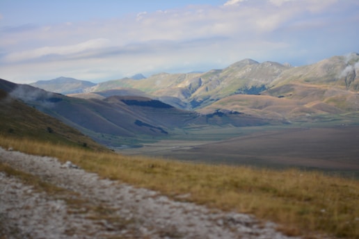 A serene landscape with a winding path leading towards distant mountains under a clear blue sky.