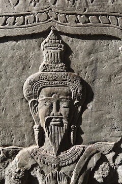 A detailed bronze relief depicting King Kosoko in regal attire against a deep royal blue background.