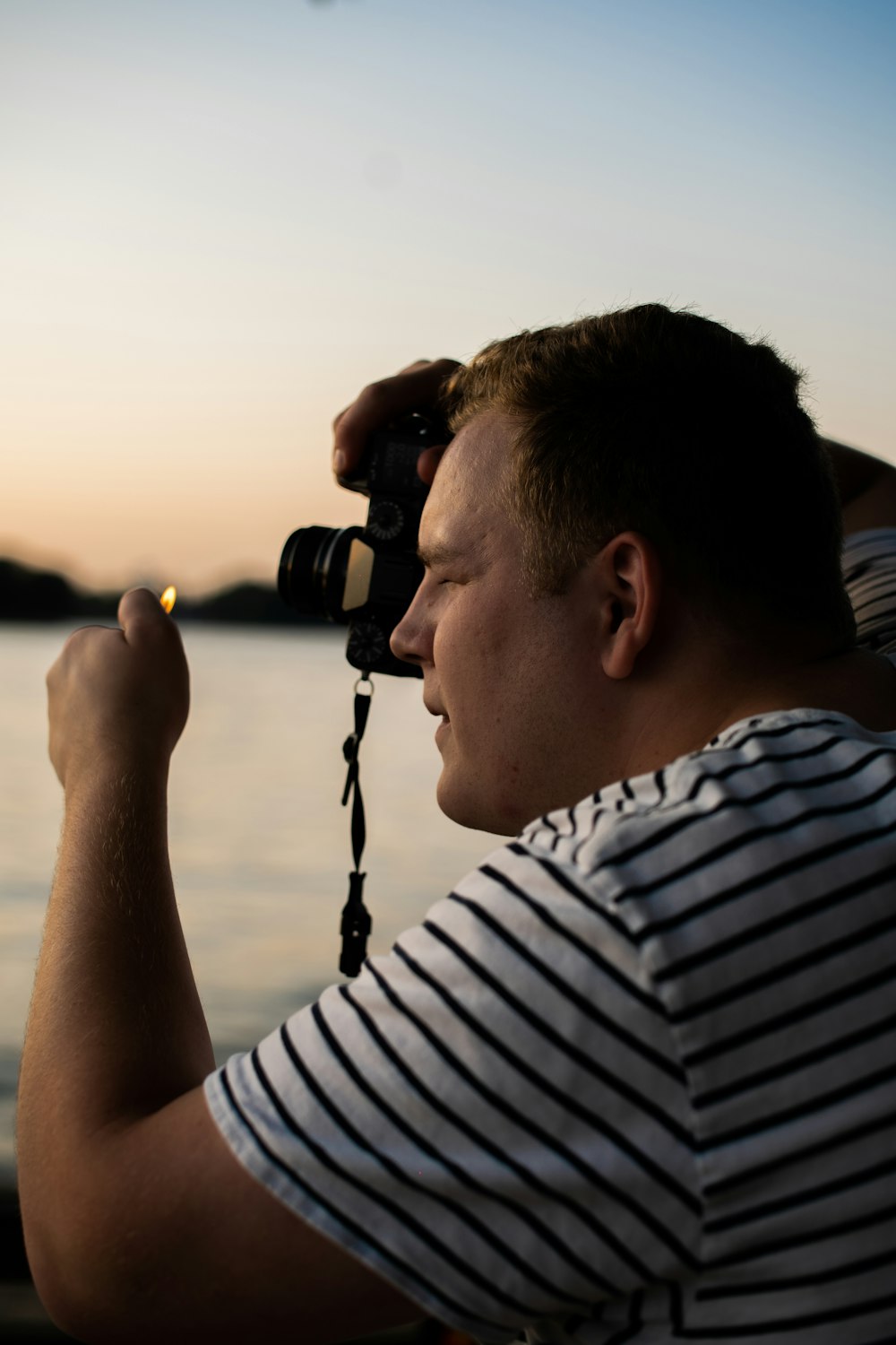 man wearing white and black striped shirt using camera