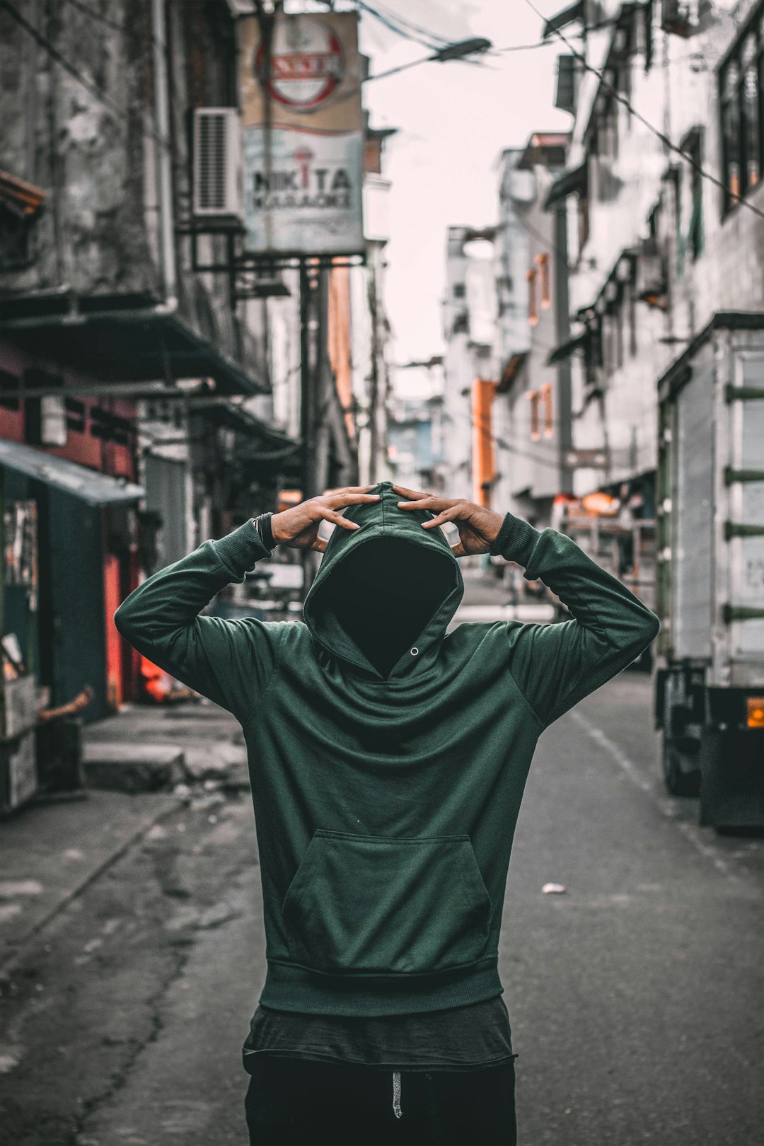 person wearing green slip on hoodie jacket near buildings during daytime