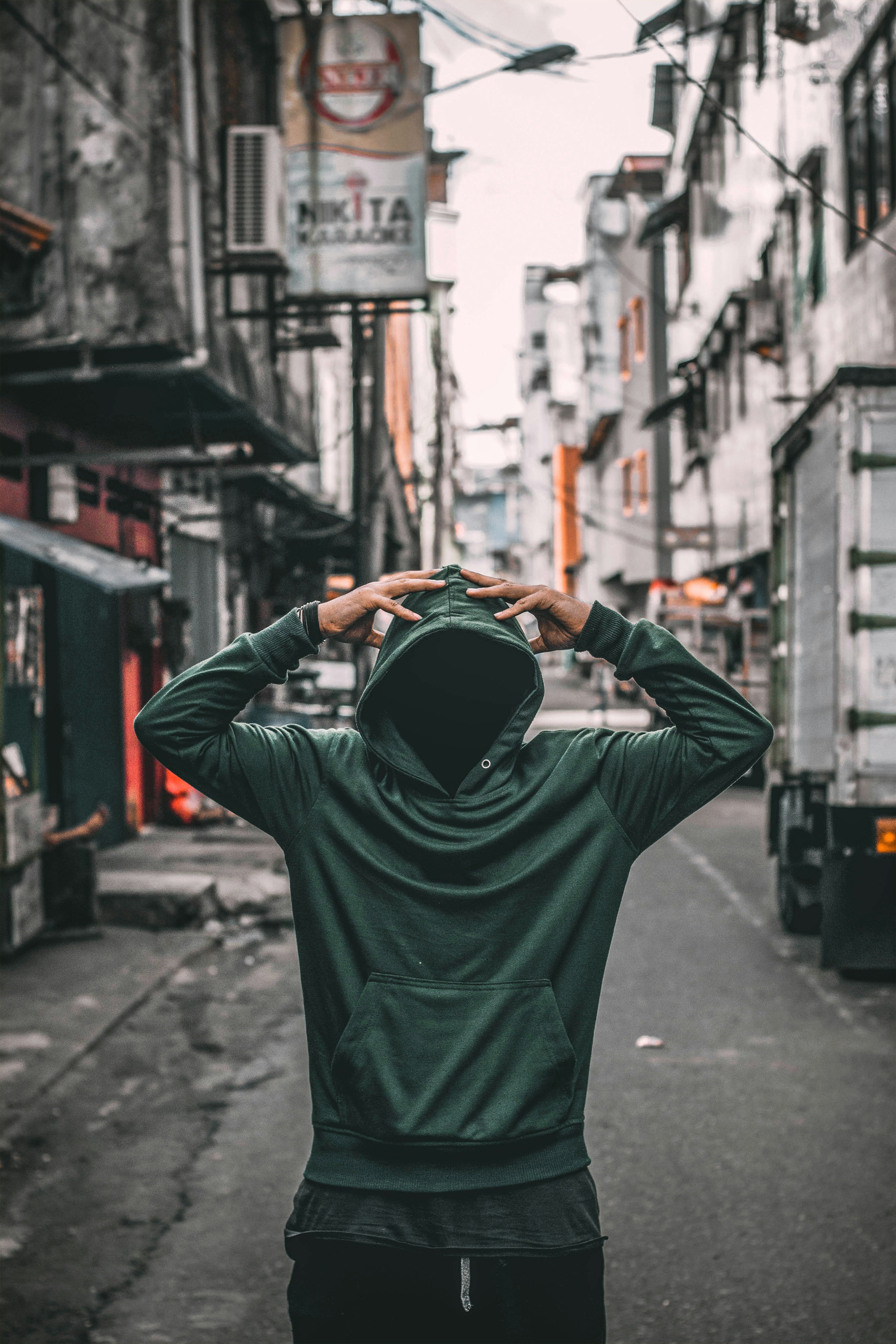 person wearing green slip on hoodie jacket near buildings during daytime