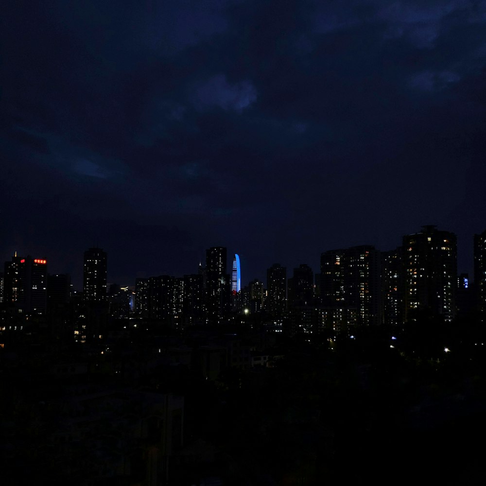 city lights turned on at night under cloudy sky