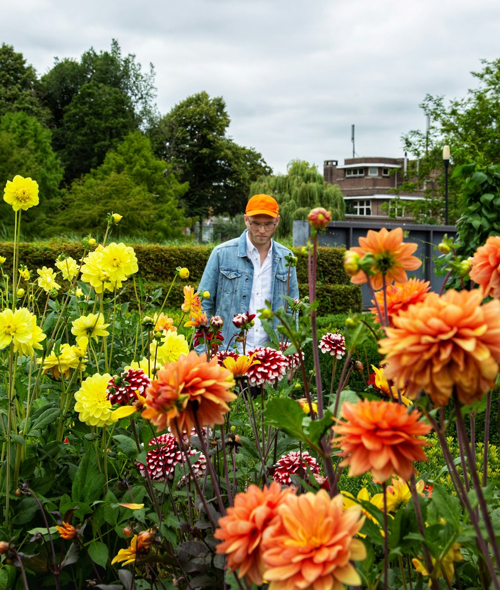 Mann in blauer Jeansjacke steht auf Blumenfeld