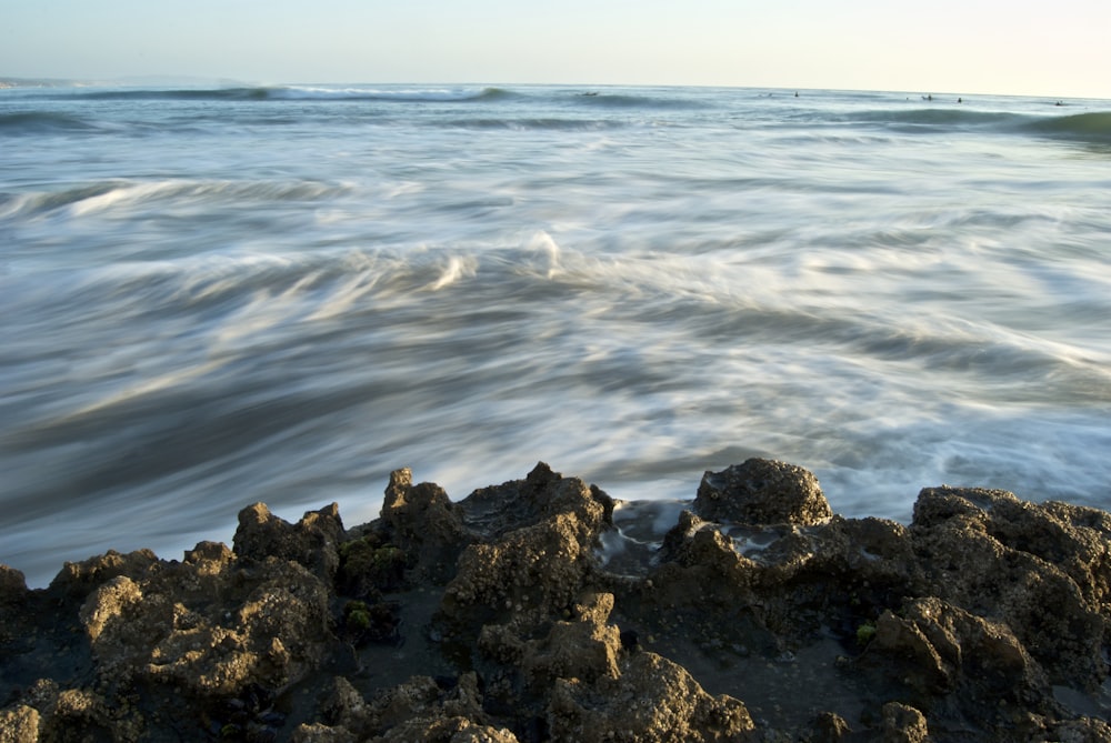 rippling body of water near brown rocks