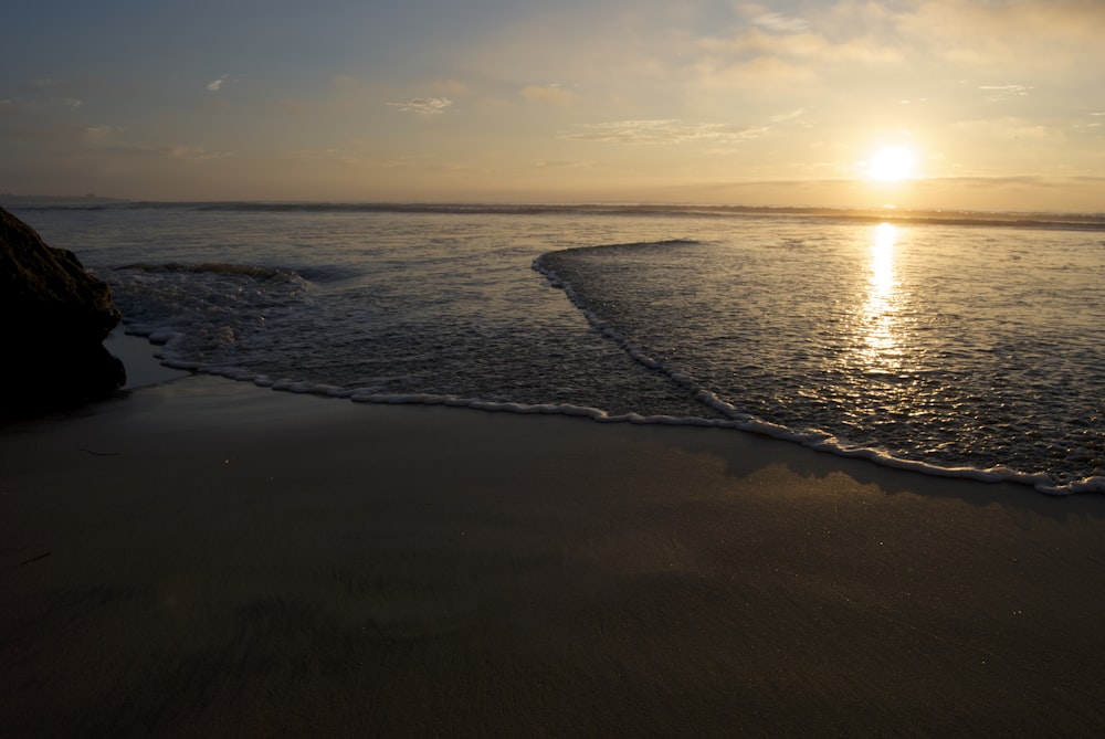 Olas marinas en la orilla del mar durante la puesta de sol