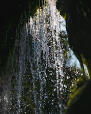 Close-up of water droplets sparkling in sunlight as they fall from a waterfall.