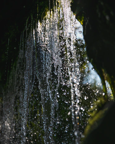 Close-up of water droplets sparkling in sunlight as they fall from a waterfall.