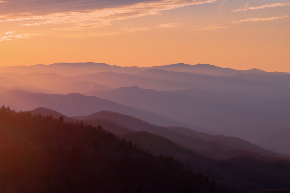 the sun is setting over a mountain range