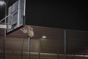 A dynamic shot of a basketball swishing through the net during a late-night streetball game
