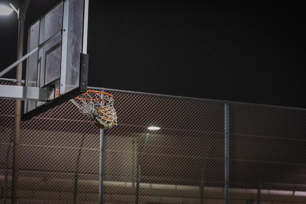 basketball hoop near gray chain link fence during night