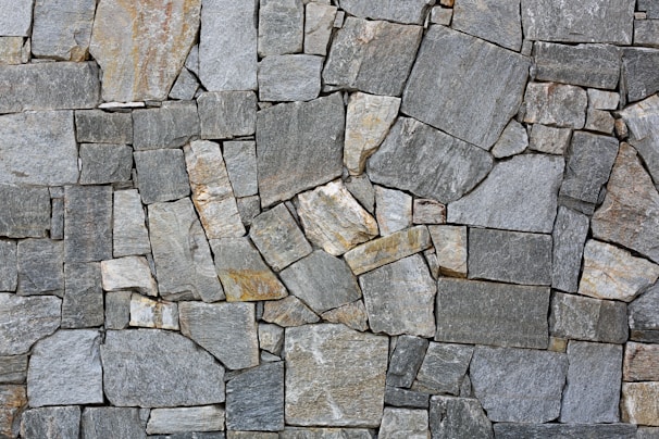 Close-up of a natural stone wall with textured beige and gray stones blending into a modern garden