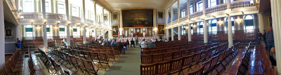 Bright, airy village hall set up for a community meeting with natural light streaming through windows.