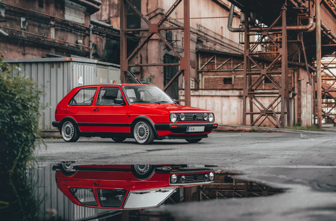 Volkswagen Golf rojo de una generación anterior junto a un edificio industrial