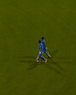 a couple of men standing on top of a lush green field