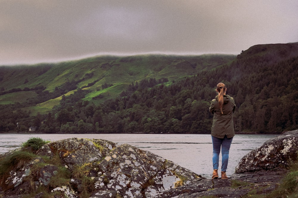 woman wearing green jacket standing across green forest