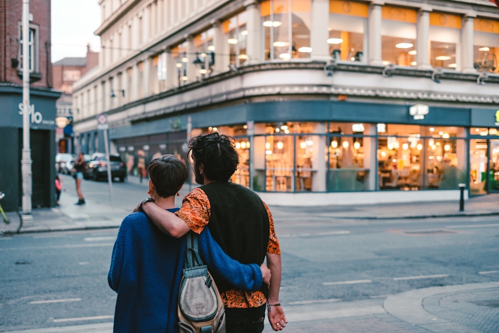 two person near a road and a building during daytime