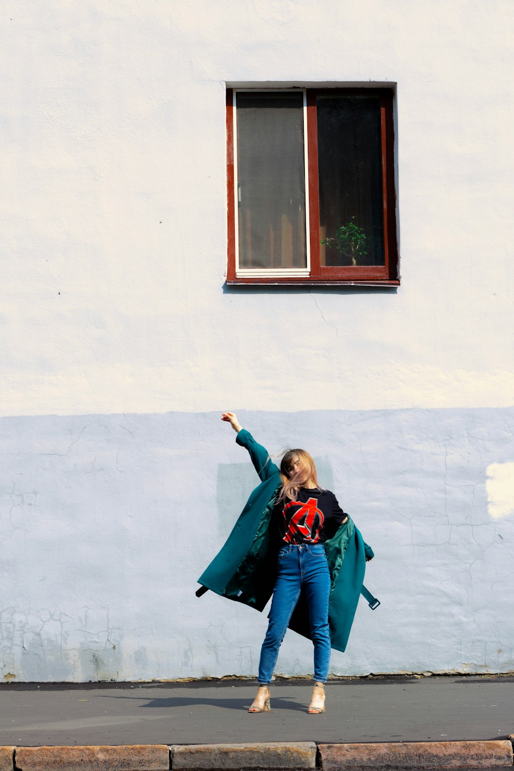 a woman standing on the side of a road in front of a building