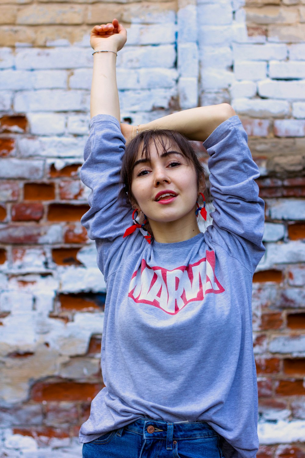 woman wearing blue and red Marvel t-shirt standing and raising right hand