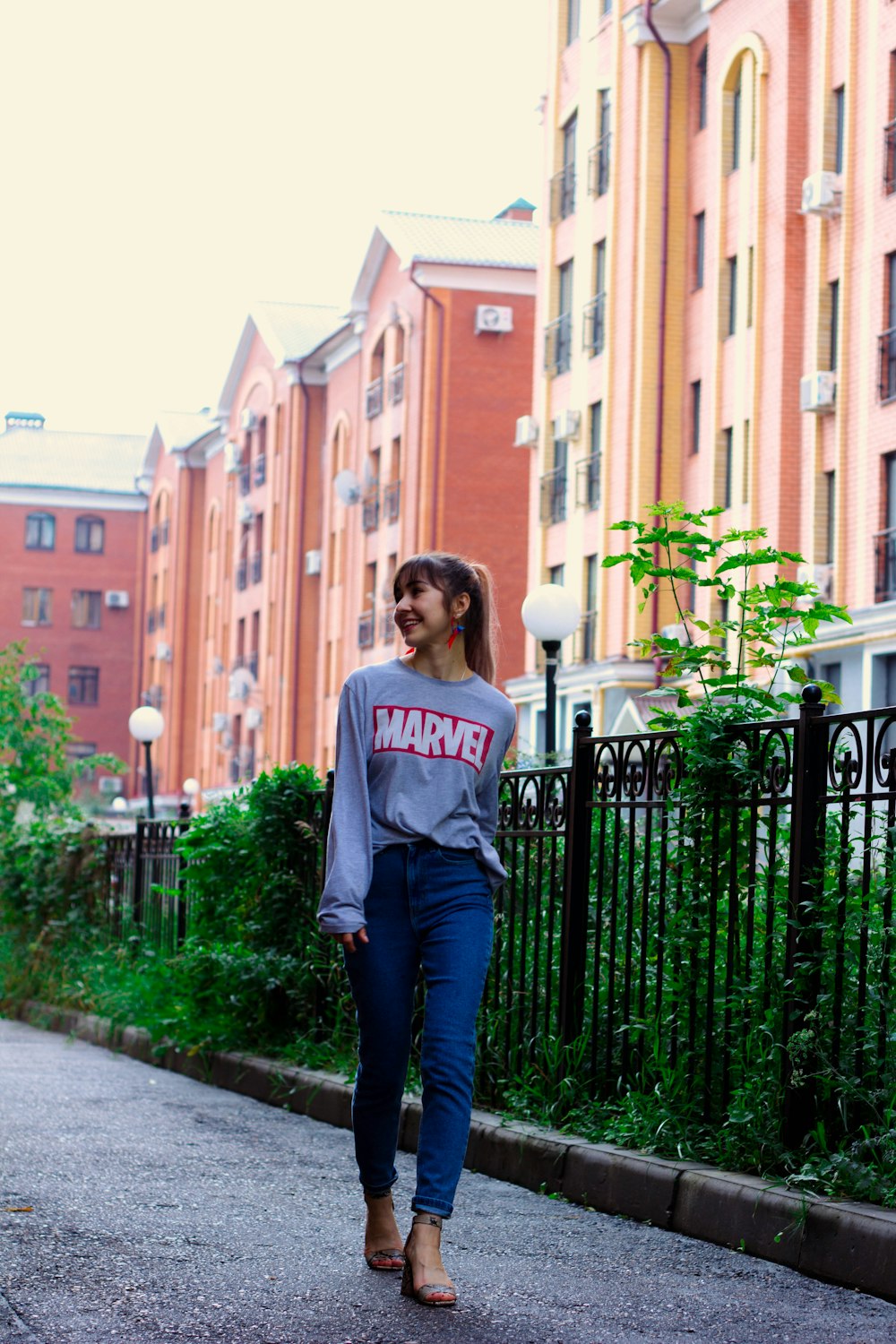 a woman walking down a street next to tall buildings