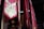 A series of vibrant red and pink fabric banners hang vertically in an indoor setting. Each banner features intricate gold and green swirling embroidery, adding a touch of elegance. The lighting is dim, with soft illumination casting shadows that enhance the rich colors and textures.