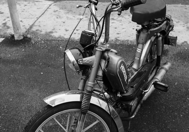 grayscale photo of moped bike on street