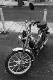 grayscale photo of moped bike on street