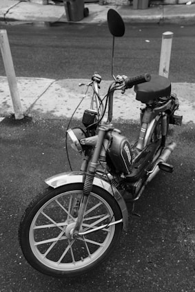 grayscale photo of moped bike on street