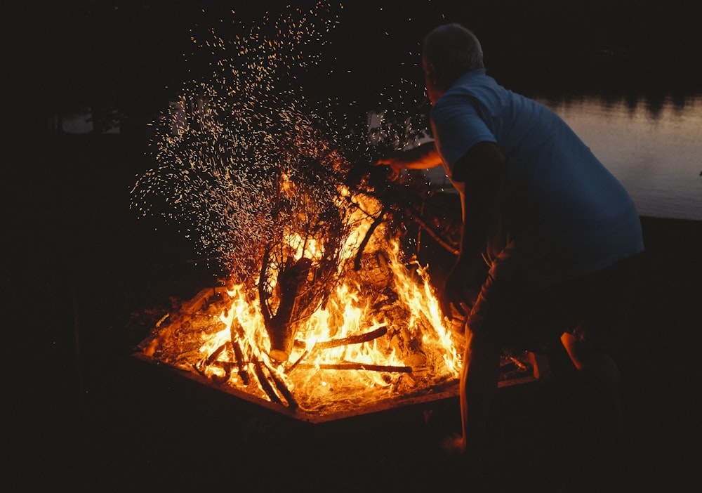 man putting woods on bonfire