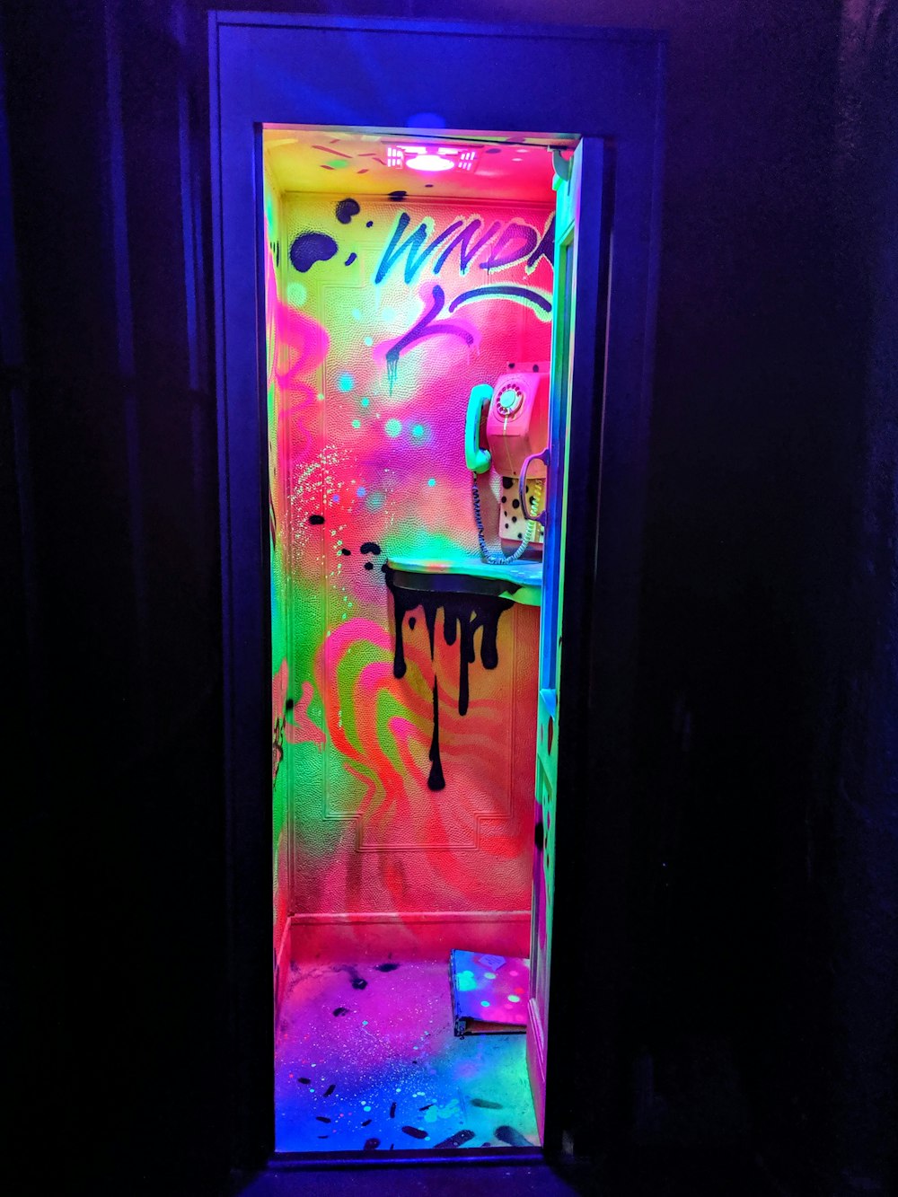 eine hell erleuchtete Toilettenkabine mit Graffiti an den Wänden