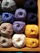 A colorful array of soft yarn skeins stacked neatly on a rustic wooden table.