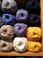 Rows of yarn spools in various warm tones, reflecting the cozy and elegant atmosphere of the brand.