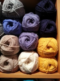 Colorful skeins of yarn arranged neatly on a wooden shelf.