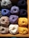Close-up of colorful wool yarn skeins neatly arranged on wooden shelves.