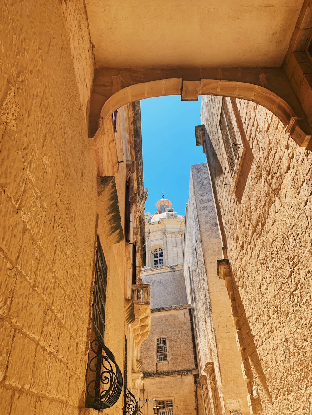 Un callejón estrecho con una torre del reloj al fondo