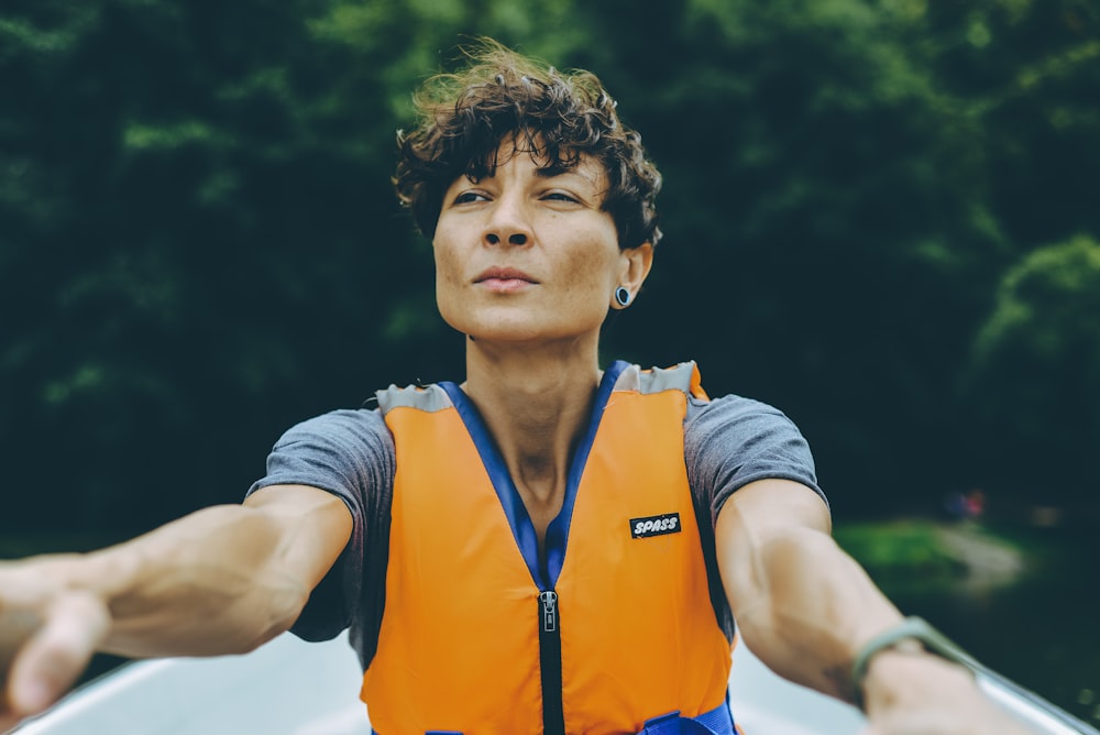 person wearing orange life vest sitting in white boat