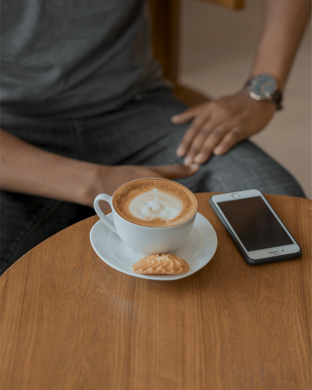 cappuccino near iPhone and man sitting beside table