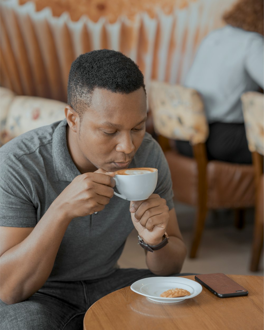 a man sitting at a table drinking a cup of coffee