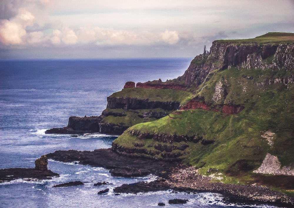 green and gray cliffs besides body of water