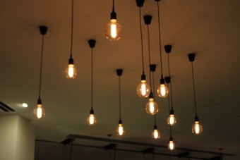 Multiple pendant lights hang from the ceiling, each with an exposed filament, creating a warm and dimly lit atmosphere.