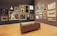 A gallery room with wooden flooring and walls displaying an eclectic collection of framed artworks, ranging from portraits to landscapes. Multiple paintings in ornate gold frames are hung on two adjacent walls, accompanied by a few sculpted busts. In the center of the room, there is a brown leather bench providing a viewing spot for visitors.