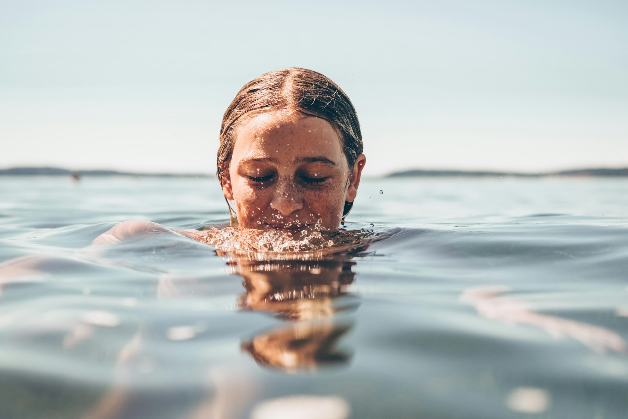 Teenage girl in the ocean with her head partially out of the water. 