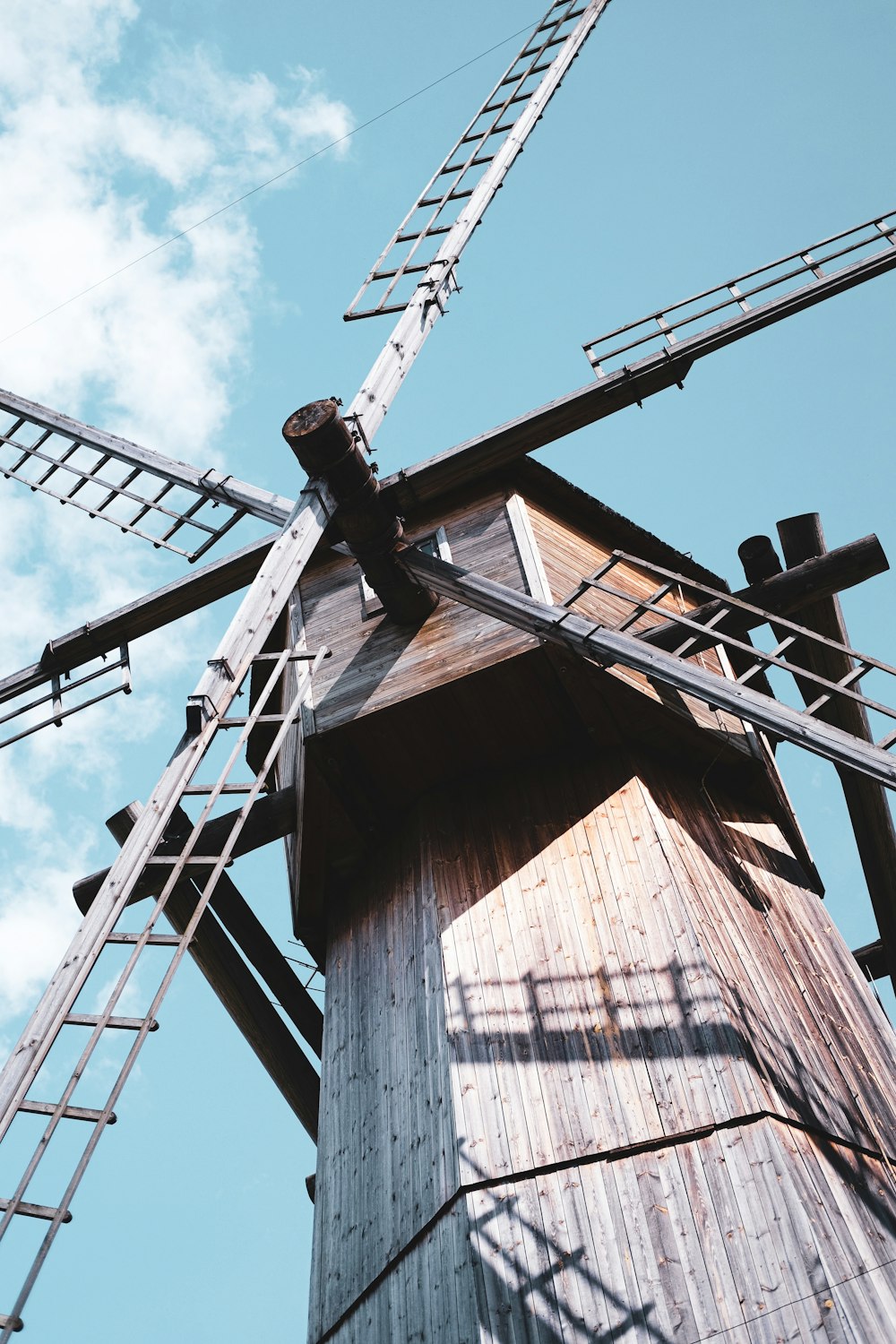 brown and gray wooden windmill under blue and white skies