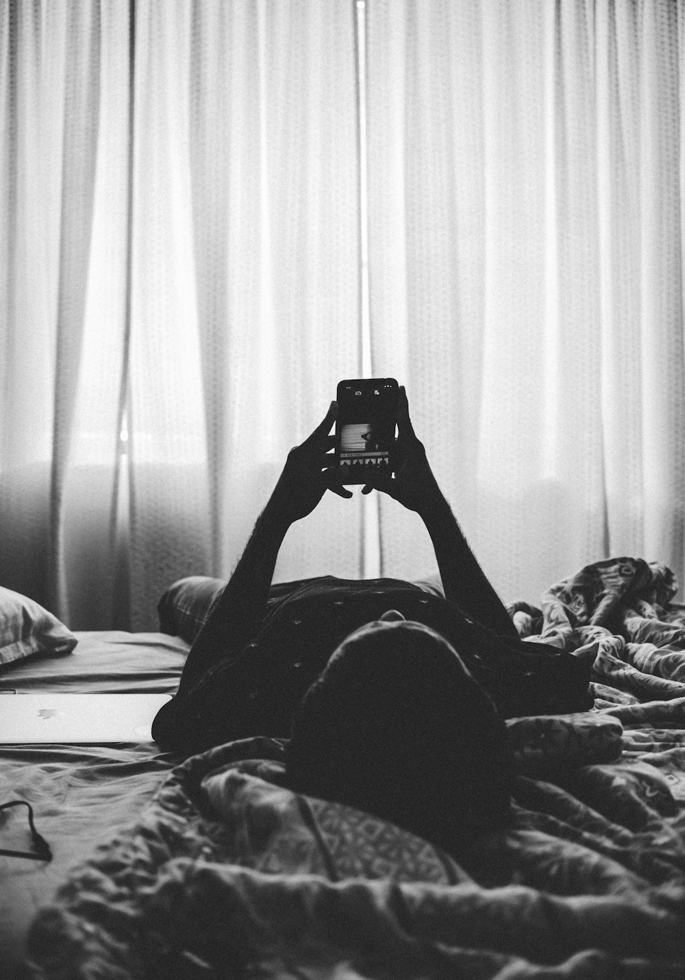 Mann liegt mit Smartphone auf dem Bett