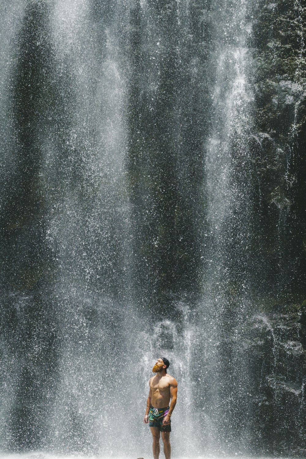 homme debout près des chutes d’eau