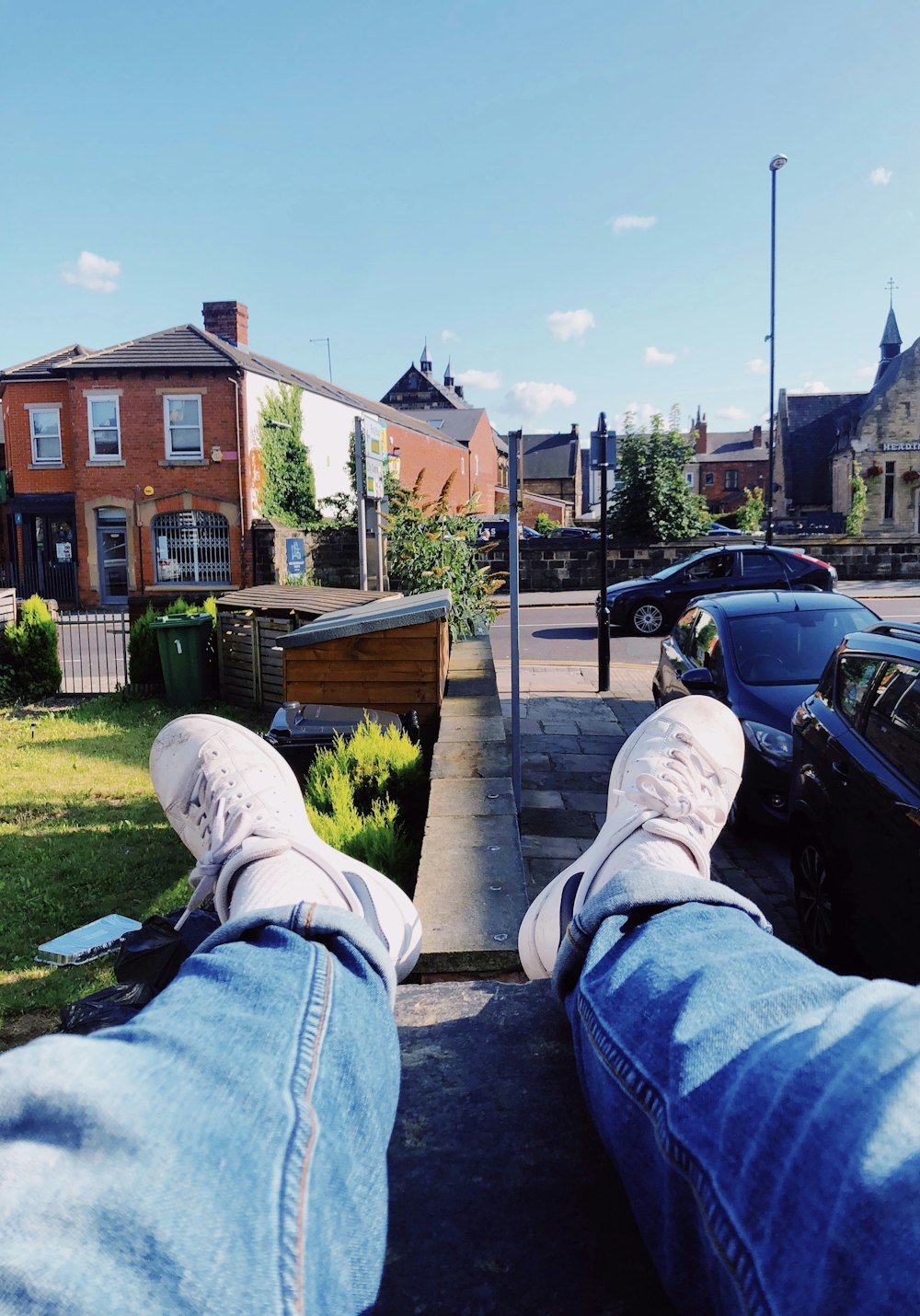 a person laying on the sidewalk with their feet up